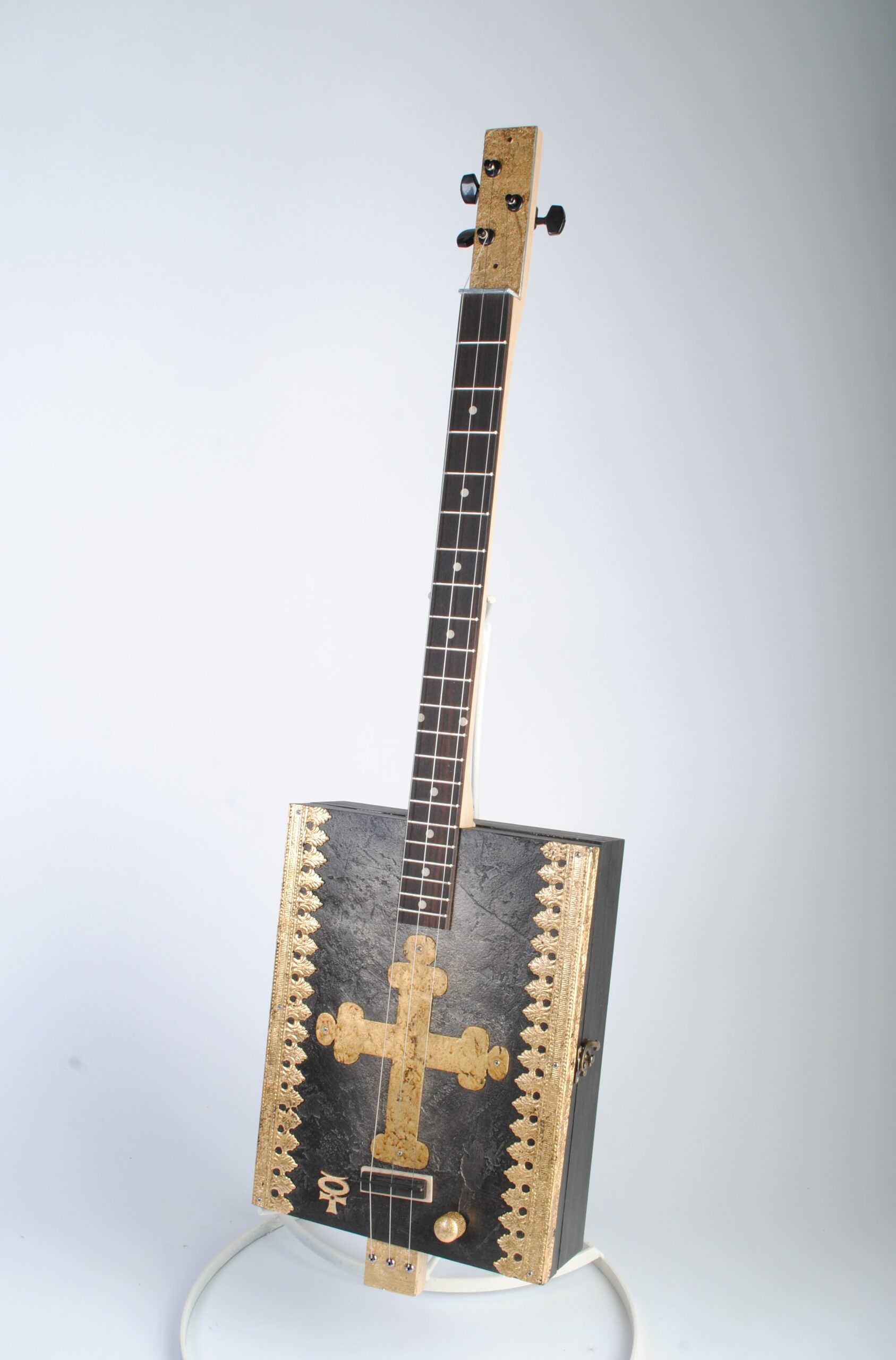 Cigar box guitar with gilded cross
